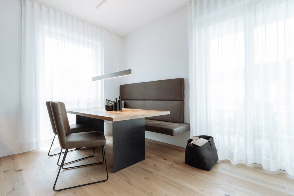Ein moderner Essbereich mit einem Esstisch aus einer massiven Tischplatte aus Eiche. Moderne Stühle und einer Sitzbank.