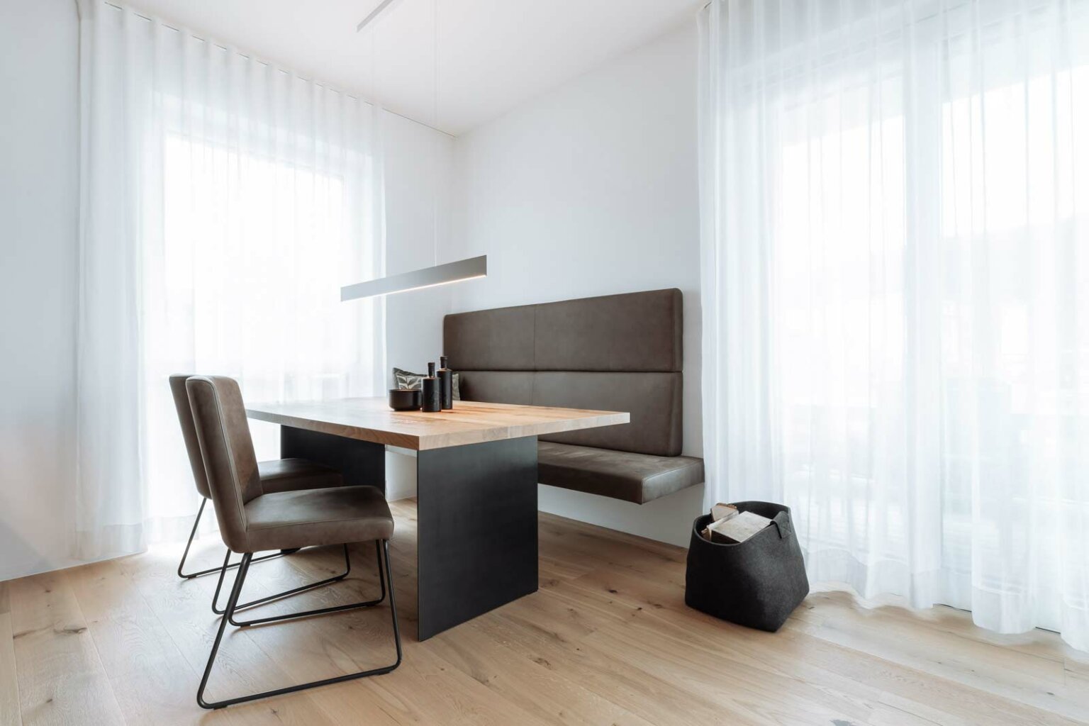 Ein moderner Essbereich mit einem Esstisch aus einer massiven Tischplatte aus Eiche. Moderne Stühle und einer Sitzbank.