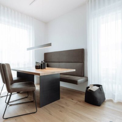 Ein moderner Essbereich mit einem Esstisch aus einer massiven Tischplatte aus Eiche. Moderne Stühle und einer Sitzbank.