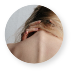 Rückenansicht einer Frau mit blondem Haar, die sich mit einer Hand den Nacken massiert, als Ausdruck von Verspannung.