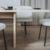 Nahaufnahme eines Holztischs mit minimalistischem Gedeck und leichtem Fokus auf Details.