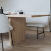 Nahaufnahme eines Holztischs mit minimalistischem Gedeck und leichtem Fokus auf Details.