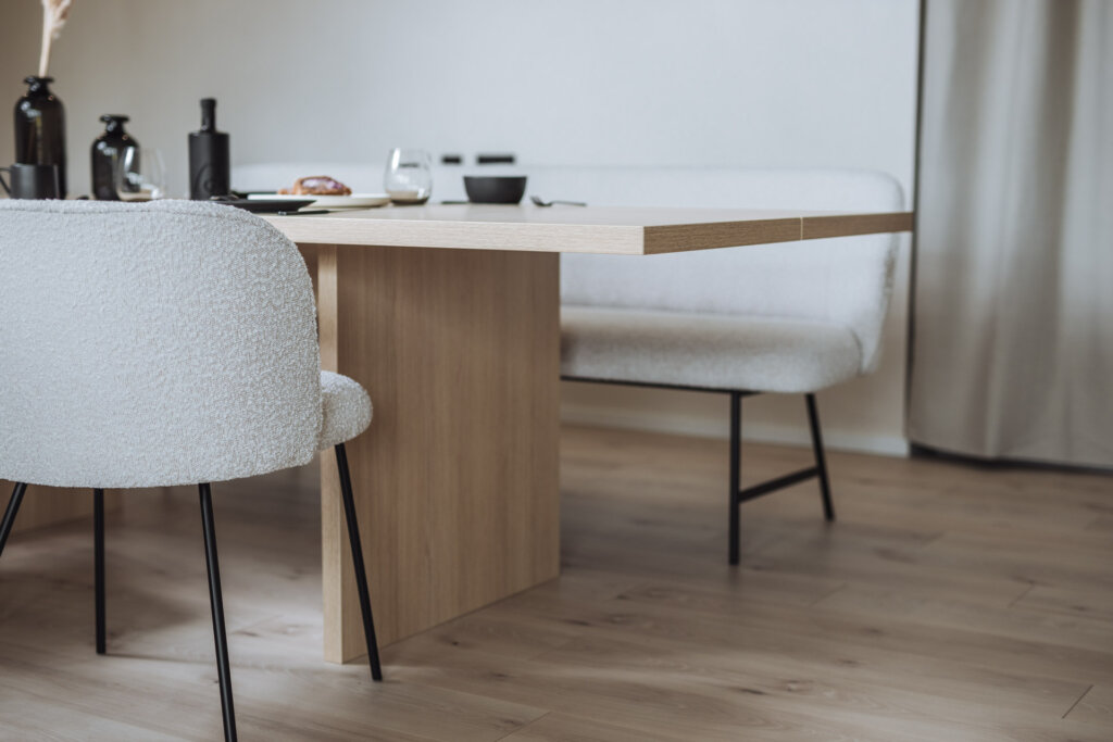 Nahaufnahme eines Holztischs mit minimalistischem Gedeck und leichtem Fokus auf Details.